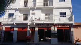 Fachada da loja com revestimento claro, letreiro e entradas vermelhas.